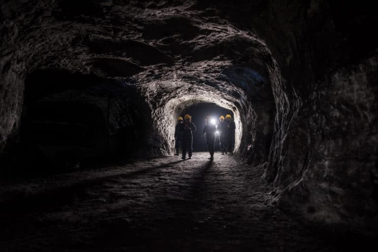 People walk into a dark underground mine.