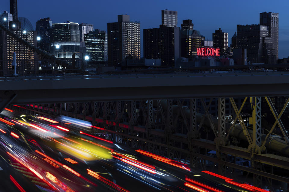 Cars drive on the Brooklyn Bridge at dusk, Monday, Nov. 14, 2022, in New York. The 8 billionth baby on Earth is about to be born on a planet that is getting hotter. But experts in climate science and population both say the two issues aren't quite as connected as they seem. (AP Photo/Julia Nikhinson)