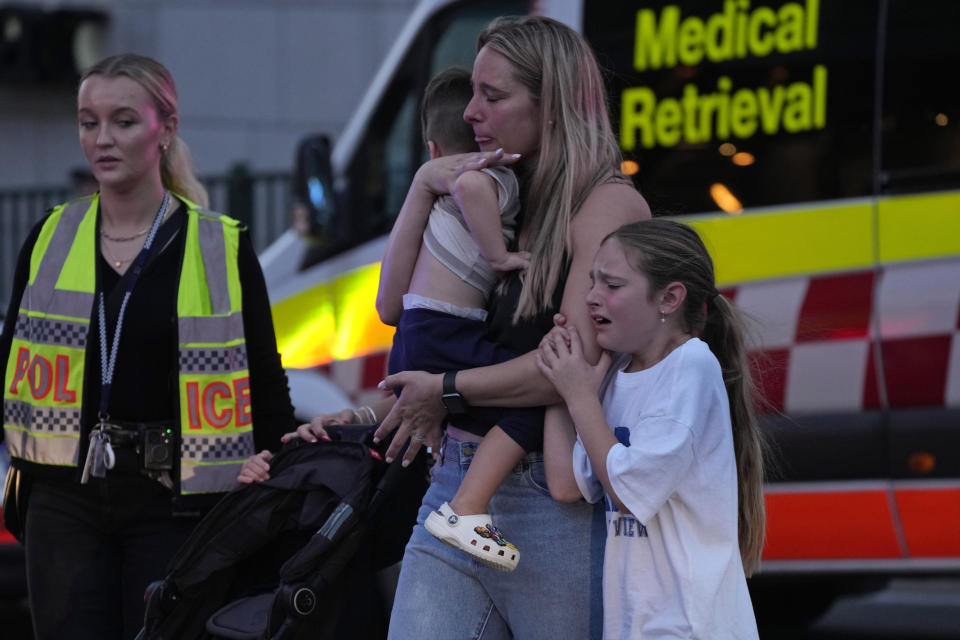 People are led out from Westfield Shopping Centre where multiple people were stabbed in Sydney, Saturday, April 13, 2024. A man stabbed six people to death at the busy Sydney shopping center Saturday before he was fatally shot, police said. (AP Photo/Rick Rycroft)