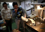 Toshio Okuma (R) holds an ivory for making 'hanko' or carved name seals at his factory in Tokyo, Japan November 28, 2016. Picture taken November 28, 2016. REUTERS/Issei Kato