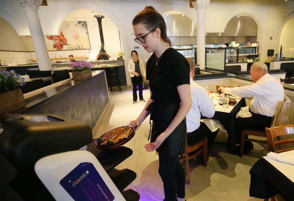 Co-owner Tiffany Chen watches as Katie Cox, a server at the new restaurant Sake Japanese Fusion, takes food from a robot to a table.