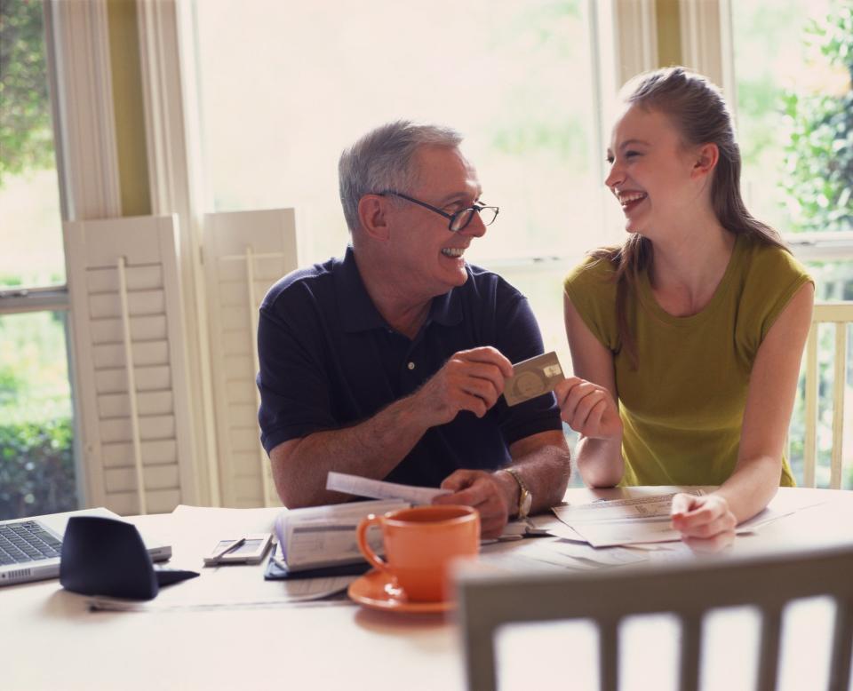 Father handing a credit card to daughter.