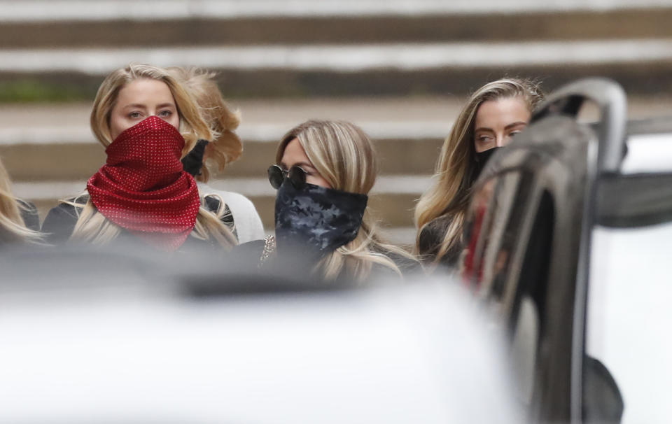 Amber Heard wears a red mask, as she departs the High Court in London, Tuesday, July 7, 2020. The libel case by actor Johnny Depp against a British tabloid newspaper started Tuesday over a 2018 article that branded him violent and abusive to then-wife Amber Heard. Depp strongly denies the claim. (AP Photo/Alastair Grant)