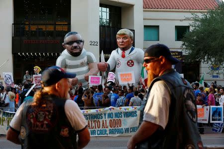 Men watch from across the street as protesters rally against Republican Presidential candidate Donald Trump, who is in town to speak on immigration, in Phoenix, Arizona, U.S. August 31, 2016. REUTERS/Nancy Wiechec