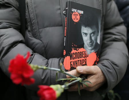 A visitor holds flowers and a book "Confessions of the Rebel" by Russian leading opposition figure Boris Nemtsov while waiting to attend a memorial service before the funeral of Nemtsov in Moscow, March 3, 2015. REUTERS/Maxim Shemetov