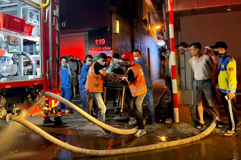 Rescue workers in Hanoi carry a victim to an ambulance following a major fire at an apartment block (Linh Dan)