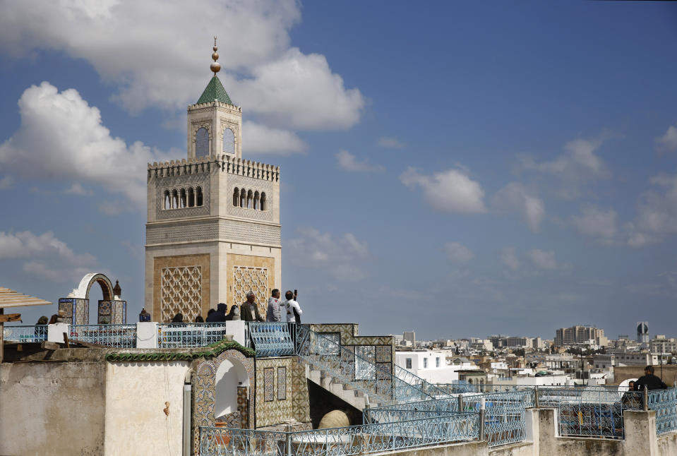 Tunisians and tourists take pictures on a rooftop coffee shop in the Old City of Tunis, Tunisia, Thursday, March 28, 2019. Tunisia is cleaning up its boulevards and securing its borders for an Arab League summit that this country hopes raises its regional profile and economic prospects. Government ministers from the 22 Arab League states are holding preparatory meetings in Tunis all week for Sunday's summit. (AP Photo/Hussein Malla)