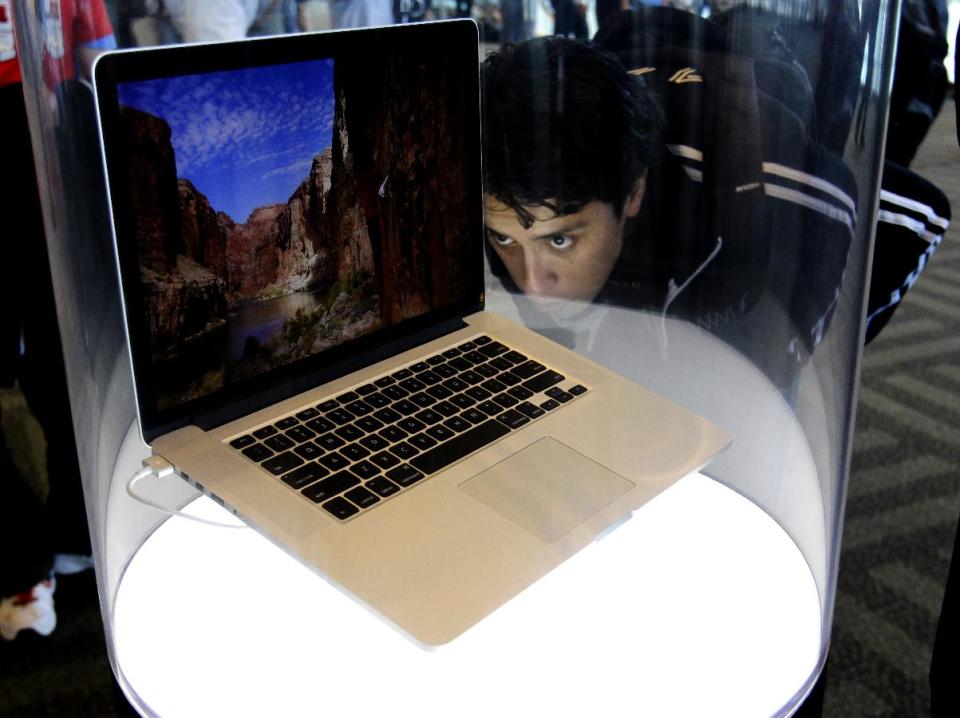 An attendee looks at the new MacBook Pro on display at the Apple Developers Conference in San Francisco, Monday, June 11, 2012. New iPhone and Mac software and updated Mac computers were among the highlights Monday at Apple Inc.'s annual conference for software developers. (AP Photo/Paul Sakuma)