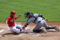 Cincinnati Reds' Nick Senzel, left, is tagged out at home plate by Chicago White Sox Yasmani Grandal during the first inning of a baseball game in Cincinnati, Wednesday, May 5, 2021. (AP Photo/Aaron Doster)