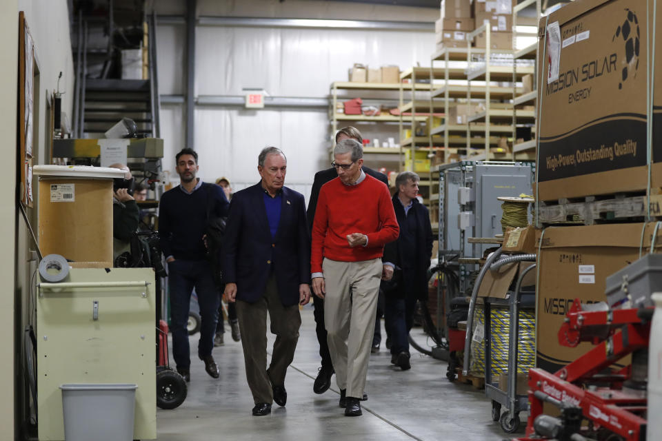 Former New York City Mayor Michael Bloomberg walks to a news conference with former Paulson Electric Company president Ron Olson, right, Tuesday, Dec. 4, 2018, in Cedar Rapids, Iowa. (AP Photo/Charlie Neibergall)