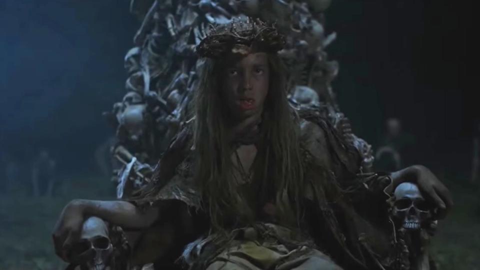 A young boy sits on a throne of skulls in American Horror Stories Feral episode