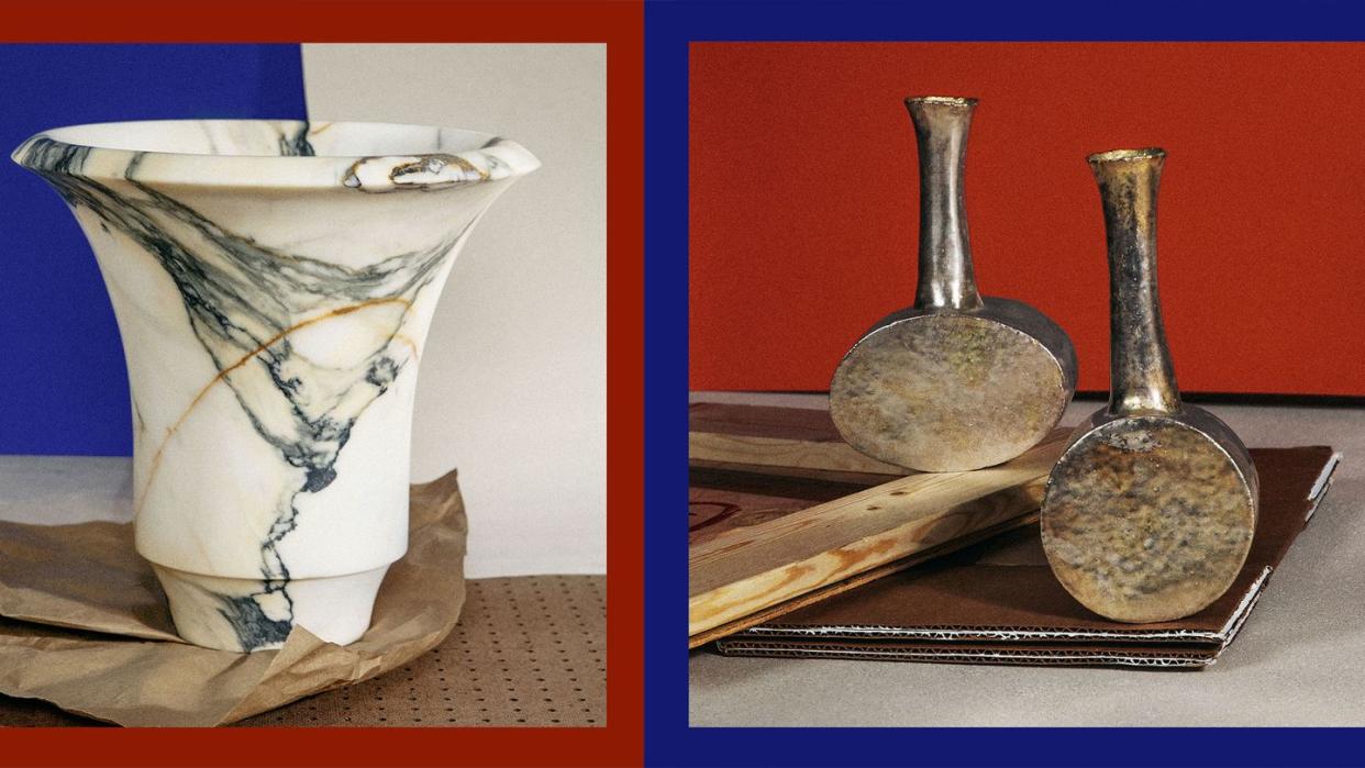 on the right a a classical looking white vase with black marbling sitting on a paper bag and on the right two small antique looking metal vases against a red background