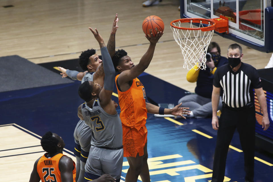 Oklahoma State forward Matthew-Alexander Moncrieffe (12) shoots while defended by West Virginia forward Gabe Osabuohien (3) during the first half of an NCAA college basketball game Saturday, March 6, 2021, in Morgantown, W.Va. (AP Photo/Kathleen Batten)