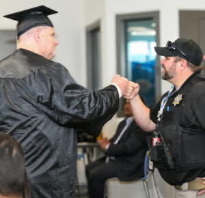  A Salt Lake Community College Prison Education Program graduate fist bumps an officer at the Utah State Correctional Facility on May 13, 2024. (Liam Truchard/Utah Department of Corrections)