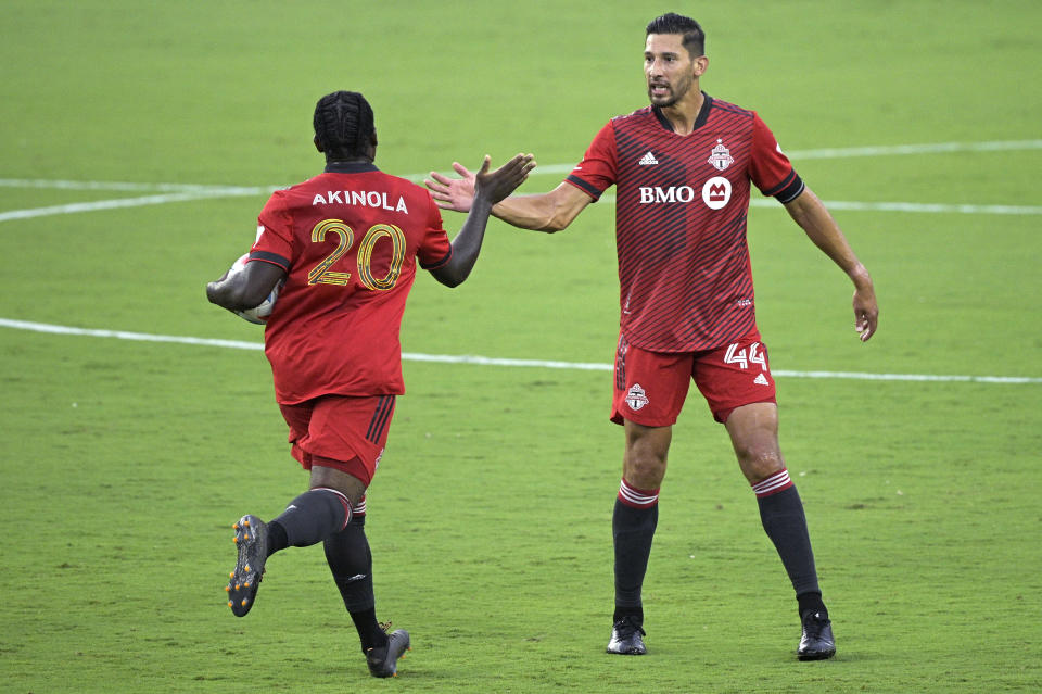 Toronto FC forward Ayo Akinola (20) is congratulated by defender Omar Gonzalez (44) after Akinola scored a goal during the first half of the team's MLS soccer match against Orlando City, Saturday, June 19, 2021, in Orlando, Fla. (AP Photo/Phelan M. Ebenhack)