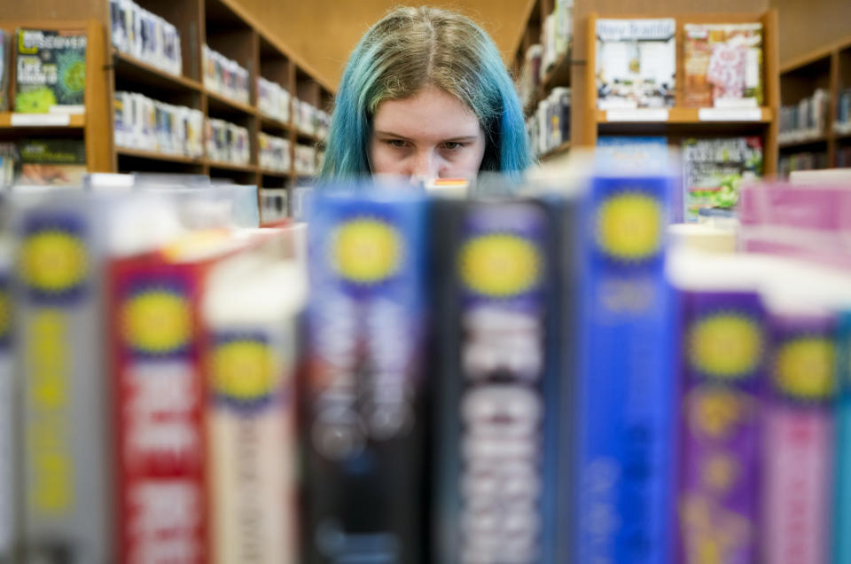 Khloe Warne, 12, browses the shelves at the Josephine Community Library, Thursday, May 18, 2023, in Grants Pass, Ore. Khloe loves drawing, writing and especially reading — in second grade, she was already reading at a sixth grade level. But she only goes to school one day a week for two hours and hasn't been on a regular school schedule for years. (AP Photo/Lindsey Wasson)