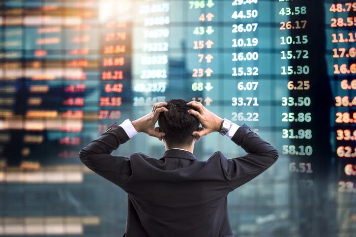 A confused investor looks at a wall of stock tickers..