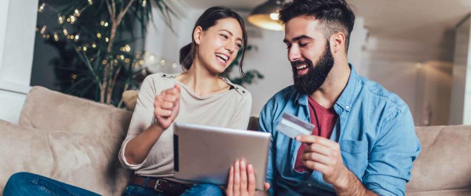 Smiling couple using digital tablet and credit card at home