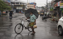 A man wearing a mask as a precaution against the coronavirus pushes his bicycle during rainfall in Kochi, Kerala state, India, Friday, Aug.7, 2020. A mudslide triggered by heavy monsoon rain and flooding killed at least five people in the state on Friday, police said. (AP Photo/R S Iyer)