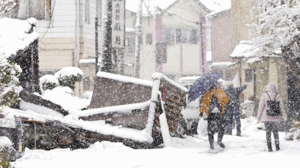 People walk past fallen buildings in the earthquake-hit Anamizu, Ishikawa prefecture, Monday, Jan. 8, 2024. Thousands of people made homeless overnight are living in weariness and uncertainty on the western coast of Japan a week after powerful earthquakes hit the region. (Kyodo News via AP)