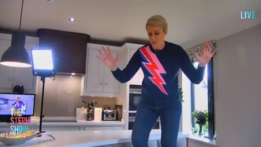 steph mcgovern in lightening print jumper standing on kitchen island