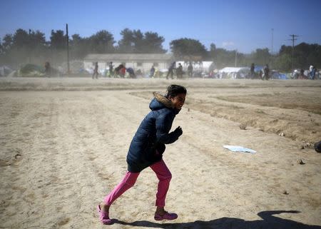A young woman walks against heavy winds and dust at a makeshift camp for migrants and refugees at the Greek-Macedonian border near the village of Idomeni, Greece, April 20, 2016. REUTERS/Stoyan Nenov