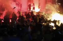 Protesters clash with riot police on the steps of the Serbian parliament during a protest in Belgrade, Serbia, Friday, July 10 2020. Hundreds of demonstrators tried to storm Serbia's parliament on Friday, clashing with police who fired tear gas during the fourth night of protests against the president's increasingly authoritarian rule. (AP Photo/Darko Vojinovic)