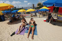 People relax in the sand at the Brooklyn Bridge Park pop-up pool on July 16, 2012 in the Brooklyn borough of New York City. A heat advisory was issued in the city again today as high temperatures were expected in the 90?s the next three days. (Photo by Mario Tama/Getty Images)