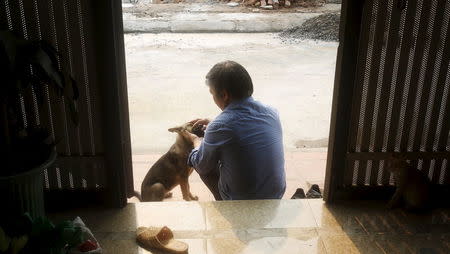 Teacher Do Viet Khoa plays with his dog at his hometown in Thuong Tin, outside Hanoi, Vietnam, April 19, 2016. REUTERS/Kham