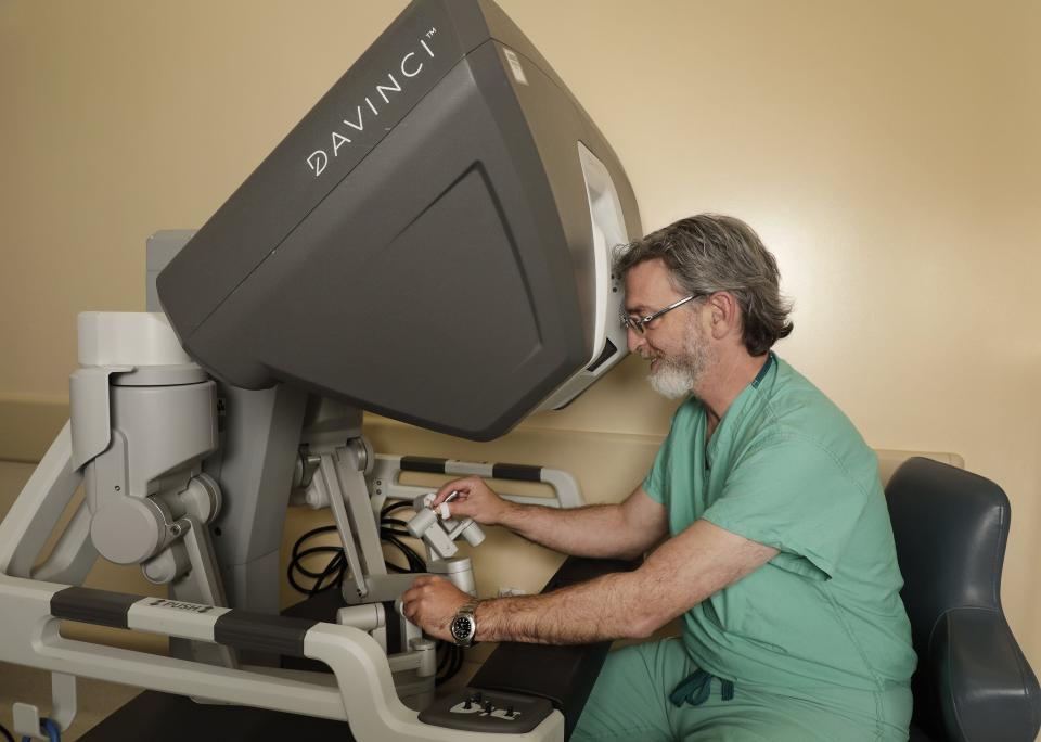 Dr. Ron Landmann, who heads the Baptist MD Anderson Cancer Center's colorectal surgery division in Jacksonville, Fla., works the controls of the da Vinci robotic surgical system. Dr. Landmann manuevers the surgical arms with the finger controls while watching the various views of the surgery on the monitor.