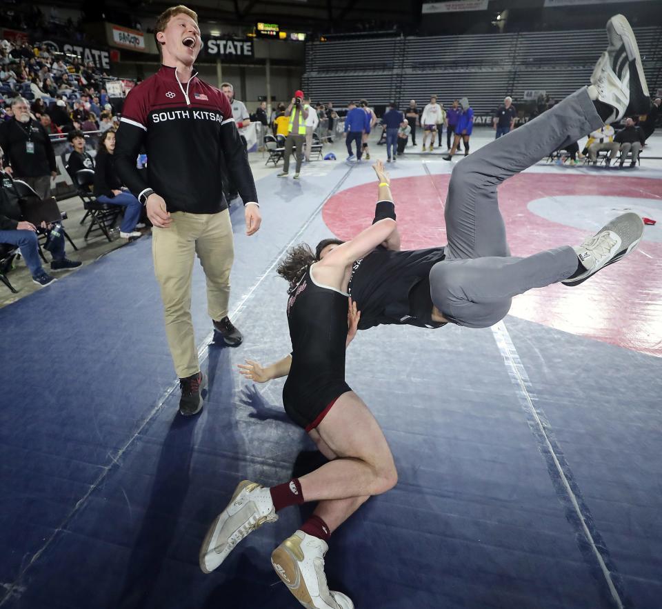 South Kitsap head coach Conner Hartmann laughs as  Phillip Chobot celebrates his 4A 182-pound first place finish by flipping one of the assistant coaches on to the mat during Mat Classic Championships at the Tacoma Dome on Saturday, Feb. 18, 2023.