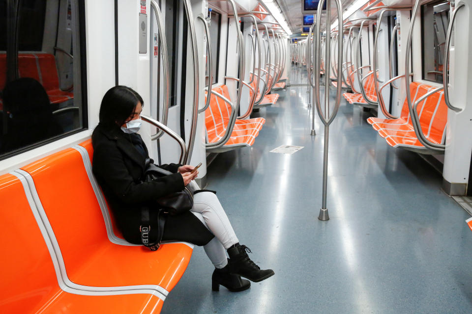 A woman wearing a protective face mask sits inside an empty metro train in Rome, on the third day of an unprecedented lockdown across of all Italy, imposed to slow the outbreak of coronavirus. (REUTERS/Remo Casilli)