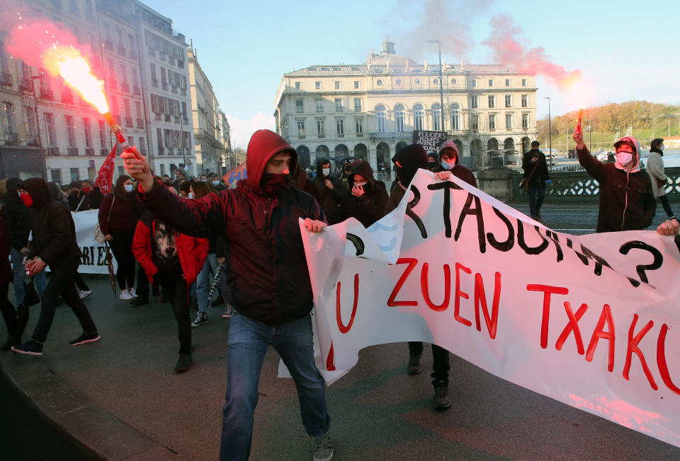 A protester holds a banner during a protest in Bayonne, southwestern France, Saturday, Dec. 12, 2020. Paris police took dozens of people into custody at what quickly became a tense and sometimes ill-tempered protest against a proposed security law. Critics fear the law could erode press freedom and make it more difficult to expose police brutality. (AP Photo/Bob Edme)