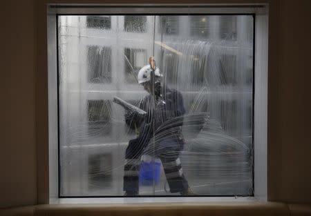 A window cleaner works on a building in the financial district of Canary Wharf in London January 22, 2015. REUTERS/Kevin Coombs