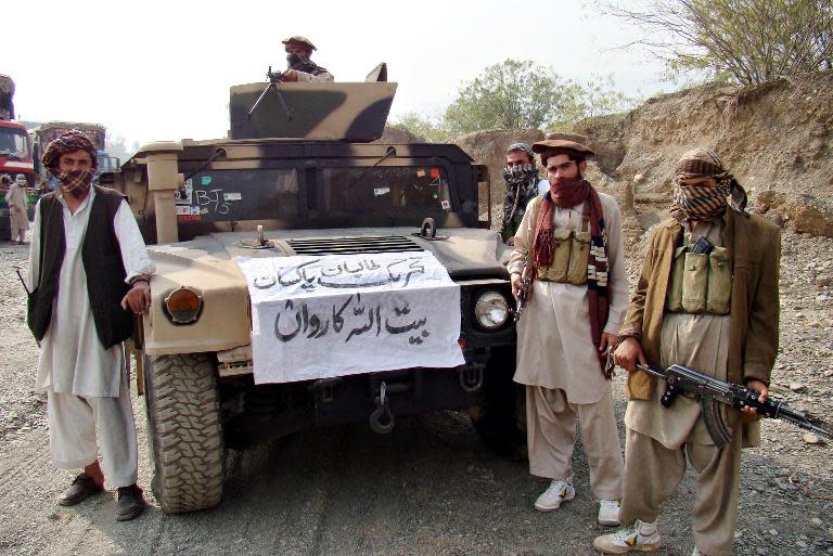 Armed militants of the Tehreek-e-Taliban Pakistan (TTP) pose for photographs next to a captured armored vehicle in Landikotal, on November 10, 2008