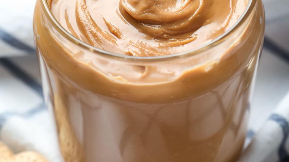 Jar with creamy peanut butter on napkin