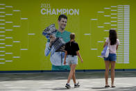 FILE - Visitors stop to take a photo of a billboard featuring defending champion Serbia's Novak Djokovic ahead of the Australian Open at Melbourne Park in Melbourne, Australia, Tuesday, Jan. 11, 2022. The drama over Djokovic's ability to defend his Australian Open title without a COVID-19 vaccine has sparked fierce public debate, but there’s little sign it threatens his multimillion-dollar sponsorship deals. It's unclear if the No. 1 seed can compete Monday, Jan. 17 after Australian officials revoked his visa for a second time. (AP Photo/Mark Baker)