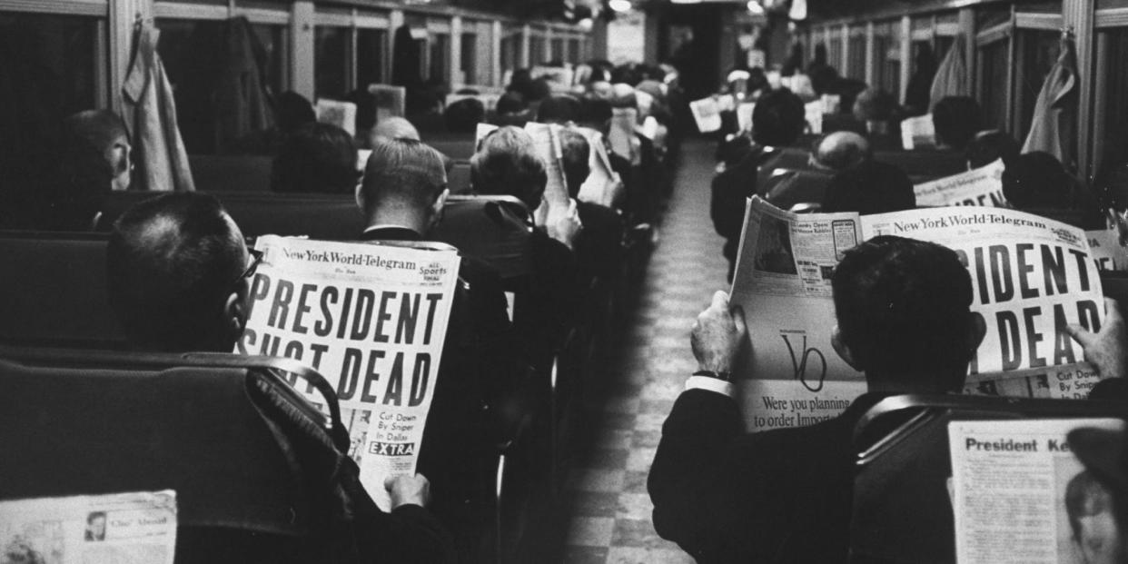 Commuters reading of John F. Kennedy's assassination.