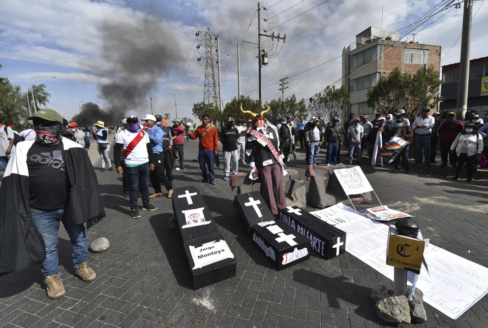 Demonstrators block a highway with mock coffins carrying the names of Peruvian President Dina Boluarte and congresspeople in Arequipa, Peru, Thursday, Jan. 19, 2023. Protesters are seeking immediate elections, Boluarte's resignation, the release of ousted President Pedro Castillo and justice for up to 48 protesters killed in clashes with police. (AP Photo/Jose Sotomayor)