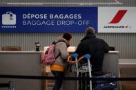Travellers stand at an Air France baggage drop-off area inside Terminal 2E at Paris Charles de Gaulle airport