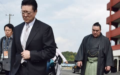 Mongolian sumo wrestler yokozuna, or grand champion, Harumafuji (R) and stable master Isegahama (L) walk towards a dormitory in Tagawa city - Credit: AFP