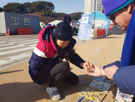 U.S. Olympic figure skater Mirai Nagasu looks at the Olympic pin collection of Bob Kalmuk (R), from California, outside the Gangneung Ice Arena during the Pyeongchang 2018 Winter Olympics, Gangneung, South Korea February 13, 2018. Picture taken February 13, 2018. REUTERS/Philip O'Connor