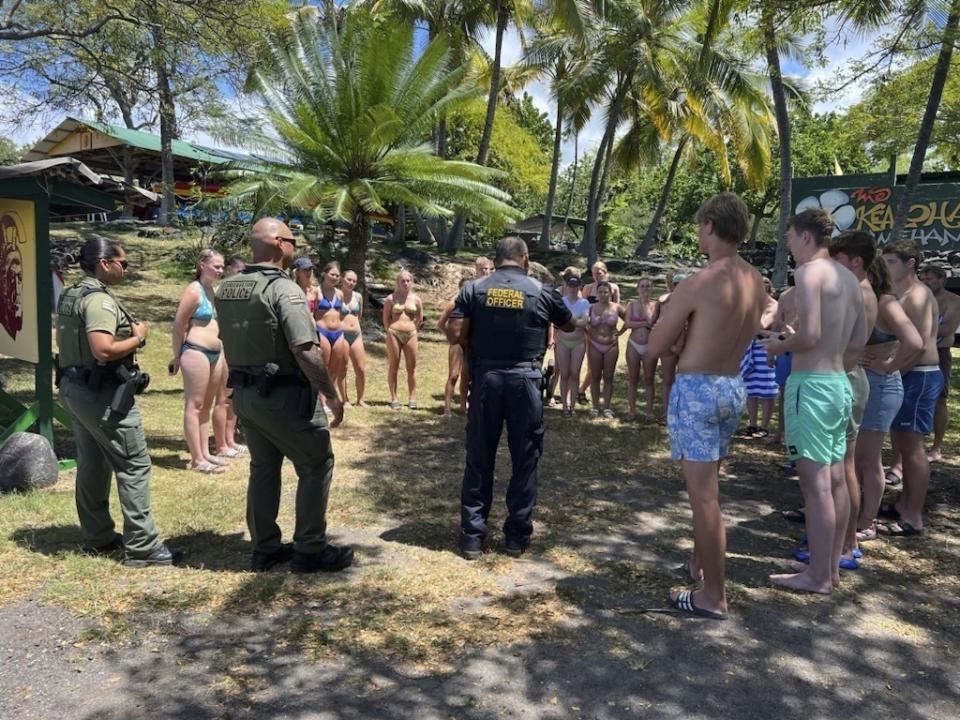 FILE - In this photo provided by the Hawaii Department of Land and Natural Resources, federal and state law enforcement officers speak to swimmers in Honaunau, Hawaii, after the swimmers allegedly harassed a pod of wild spinner dolphins on March 26, 2023. Taking care of Hawaii's unique natural environment costs money and now the state wants tourists to help pay for it, especially because growing numbers are traveling to the islands to enjoy the beauty of its outdoors — including some lured by dramatic vistas they've seen on social media. (Hawaii Department of Land and Natural Resources via AP, File)