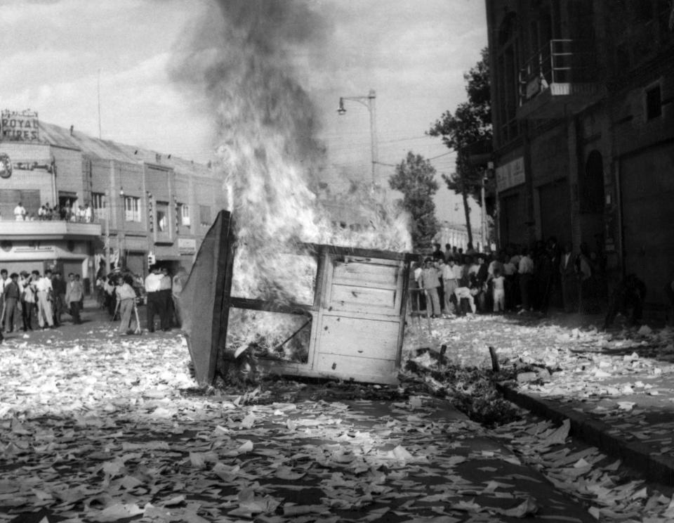 FILE - This Aug. 19, 1953 file photo shows a Communist newspaper kiosk burned by pro-shah demonstrators after the coup d'etat which ousted Prime Minister Mohammad Mossadegh, in Tehran, Iran. In 2018, as Iran deals with President Donald Trump's decision to pull America from the nuclear deal with world powers, more are invoking the 1953 CIA-backed coup that toppled Mossadegh as proof the U.S. cannot be trusted. (AP Photo, File)