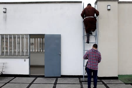 Venezuelan priest Luis Antonio Salazar climbs on a rooftop seeking for a location to record a video for his social media in Caracas