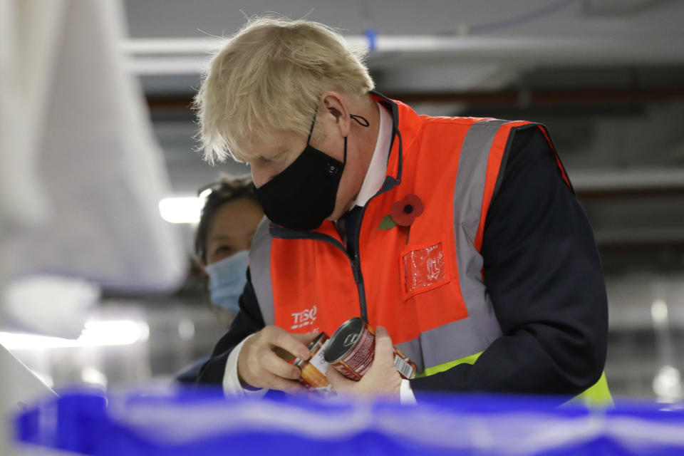 Britain's Prime Minister Boris Johnson loads produce into baskets during a visit to a tesco.com distribution centre in London, Wednesday, Nov. 11, 2020. (AP Photo/Kirsty Wigglesworth, pool)