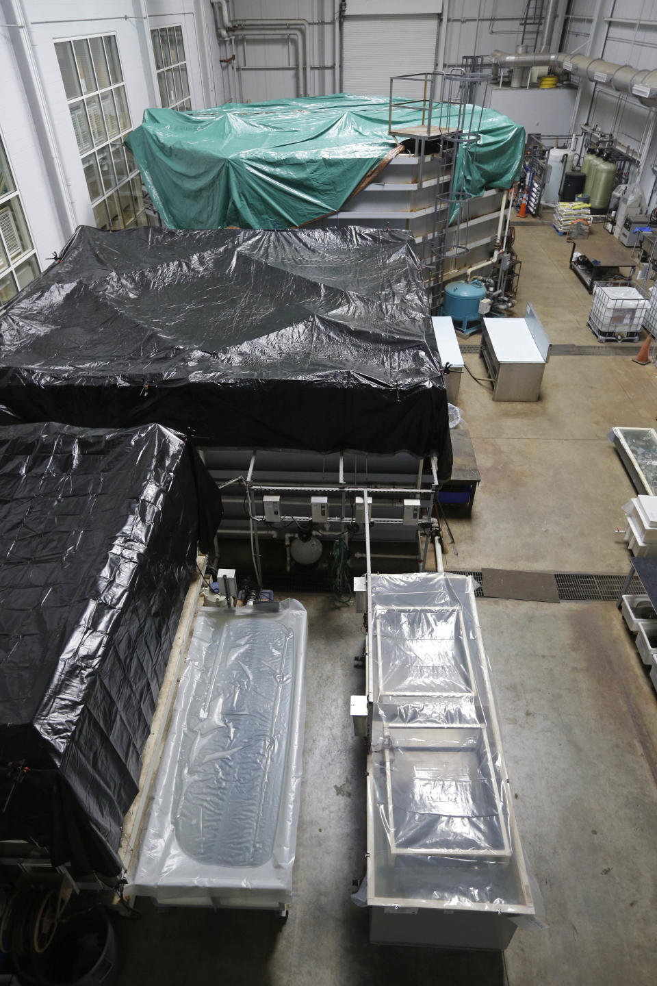 The tanks containing the turret, engine, cannons as other artifacts from the USS Monitor in the wet lab are closed and covered at the Mariners Museum in Newport News, Va., Tuesday, Jan. 21, 2014. The museum is facing federal funding shortfalls that threaten to delay the conservation of the USS Monitor artifacts. The museum has seen a steady decline in annual funding from the National Oceanic and Atmospheric Administration amid budget cuts and shifting federal priorities. The turret is in the tank with the green tarp and the steam engine is in the large tank with the black tarp. (AP Photo/Steve Helber)