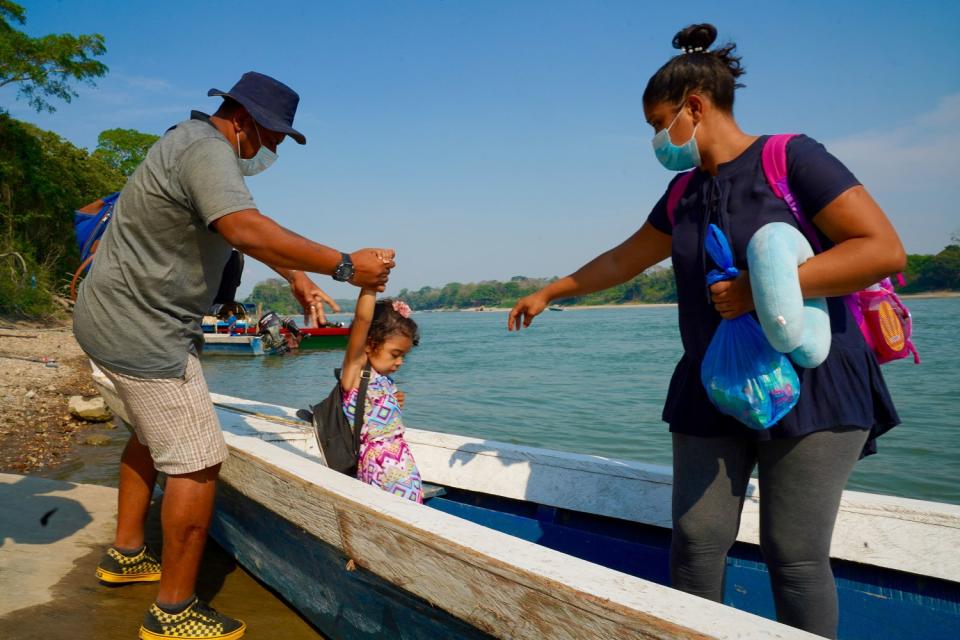 A man helps a child into a boat that a woman is standing in.