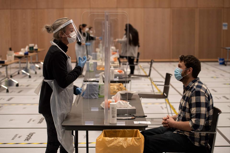 A member of staff instructs a student on how to self-administer a swab for a lateral flow Covid-19 test at the University of Hull (AFP via Getty Images)