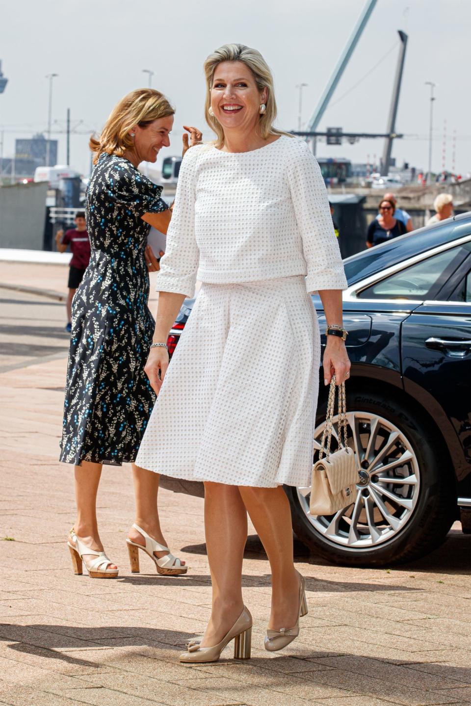 <p>Para cumplir con sus labores de reina, la monarca eligió este conjunto de falda y top blancos con efecto perforado y accesorios color beige. </p>